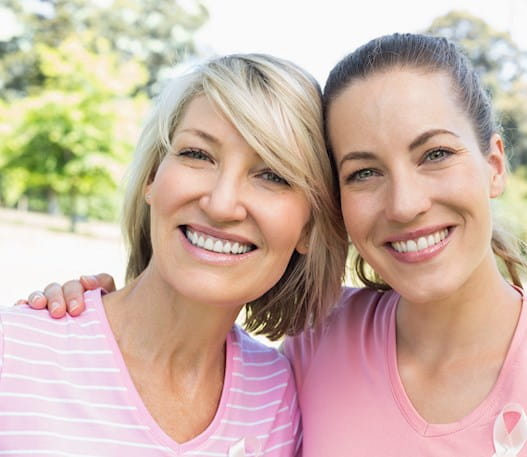 Two smiling women wearing pink shirts 
