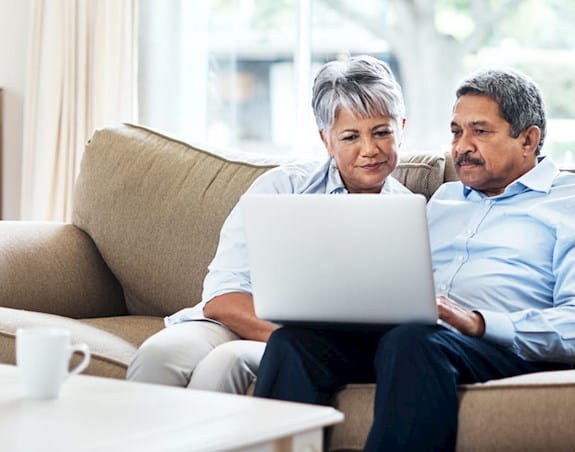 A couple on a couch looking at a laptop together