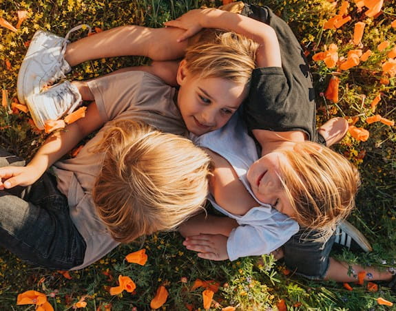 Three young boys are playing together on a grassy field