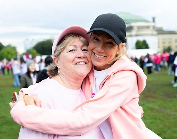 Two women wearing hats hugging and smiling at the camera