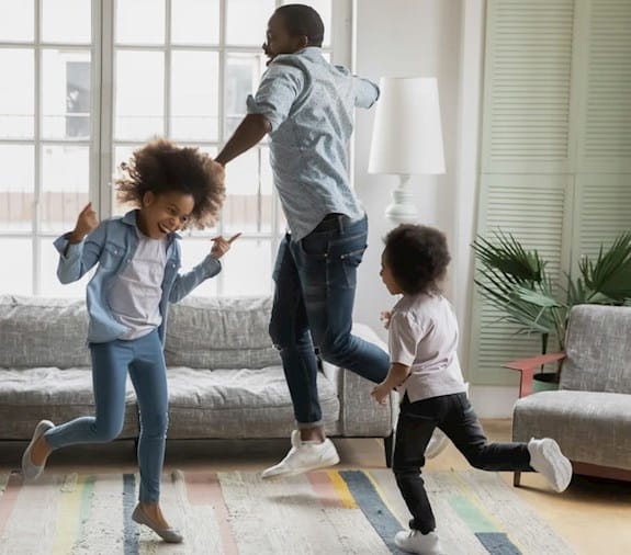 Père et ses deux filles dansant dans leur salon.