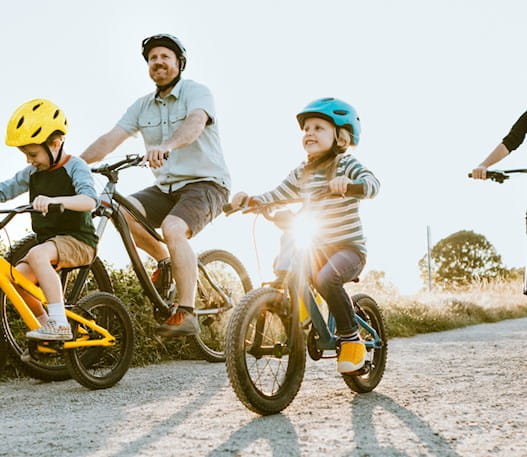 Un père et une mère et leurs deux enfants faisant du vélo sur un chemin