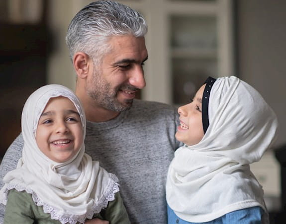 Un père avec ses deux jeunes filles portant des hijabs.