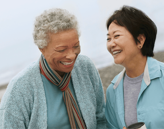Deux dames âgées riant ensemble à la plage.